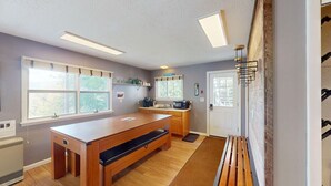 Eine moderne Küche mit Holztisch, eingebauter Mikrowelle und einem Fenster mit Jalousien.