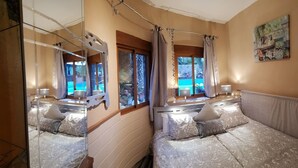 Ein Zimmer mit Spiegel, Bett, Fenster und einem Bild an der Wand.