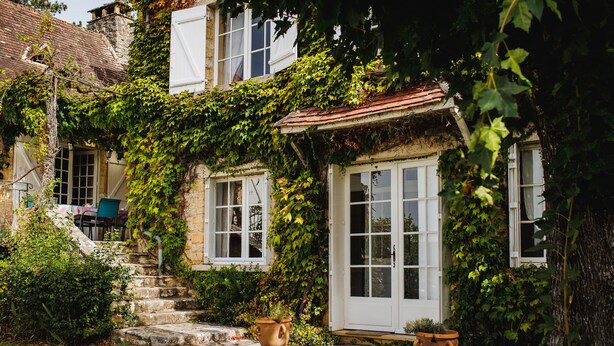 Un bâtiment en pierre aux murs recouverts de lierre et doté d’un toit traditionnel en tuiles.