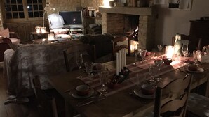 Un coin repas chaleureux avec une table en bois dressée pour le repas, une cheminée et un téléviseur en arrière-plan.