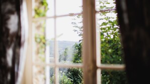Une fenêtre donnant sur un paysage verdoyant et des collines.