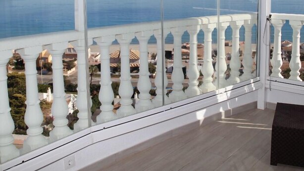 A room with large windows offering a view of the sea and a distant island.