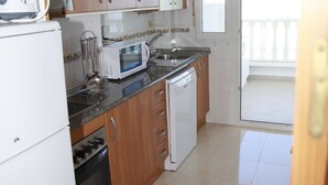 A kitchen with wooden cabinets, a microwave, a dishwasher, and a refrigerator.