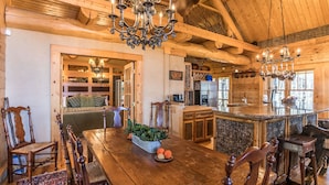 A rustic wooden interior with a dining area, a kitchen, and a cozy seating area. - Red Stag Lodge at Eagles Nest: Hot tub, game room, outdoor fireplace, summer concerts (Banner Elk)