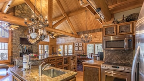 A spacious kitchen with granite countertops, stainless steel appliances, and wooden beams. - Red Stag Lodge at Eagles Nest: Hot tub, game room, outdoor fireplace, summer concerts (Banner Elk)