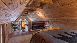 Een houten interieur met een schuine kap, een trap en uitzicht door een raam.