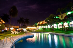 Una piscina al aire libre, sombrillas, sillones reclinables de piscina
