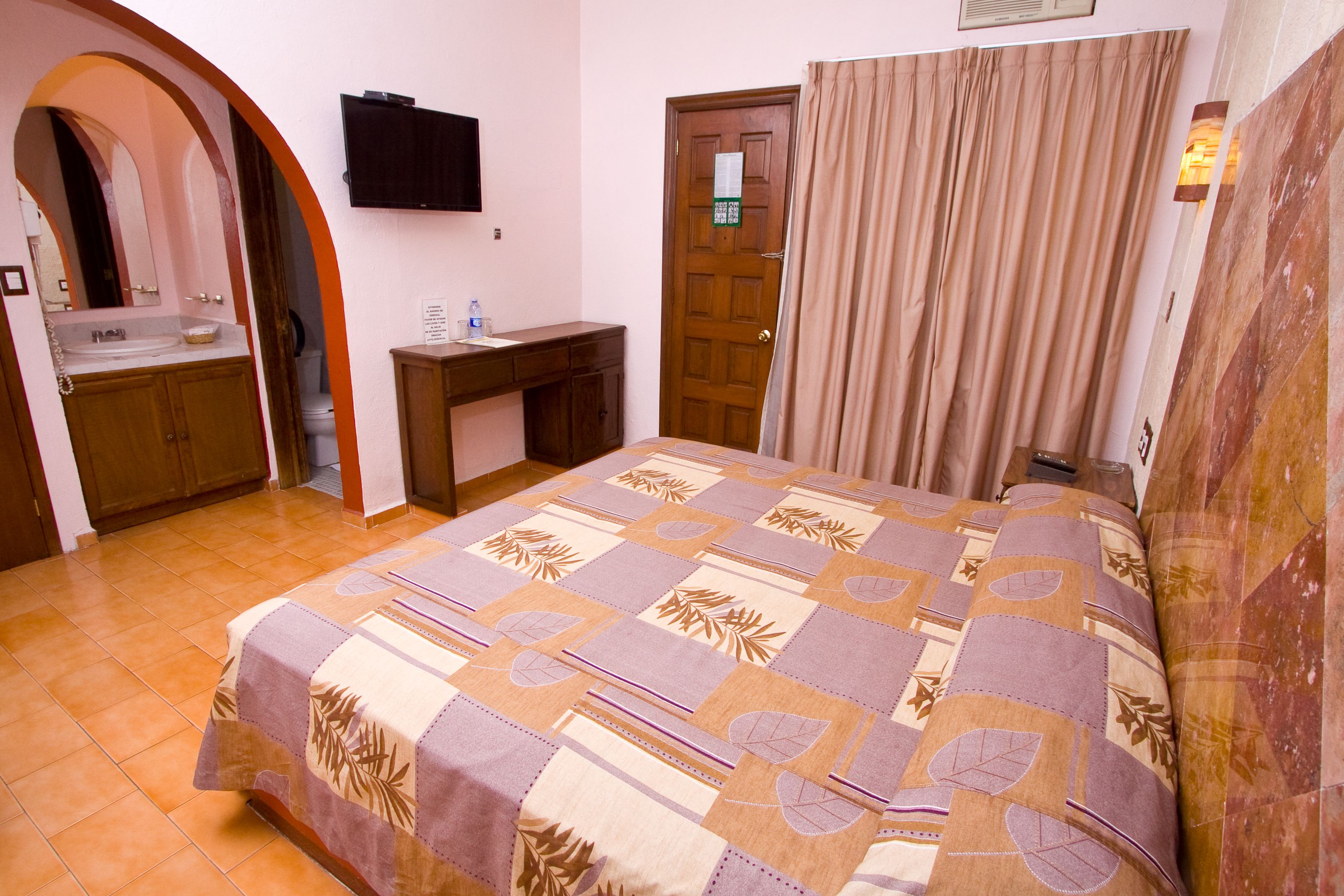 Un dormitorio con cama, escritorio, lavamanos y puerta.