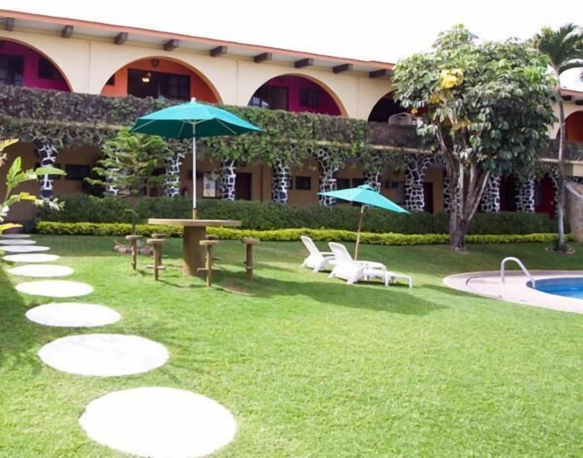 Ein Innenhof mit Pool, Liegestühlen und einem Tisch mit Sonnenschirmen.