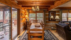 Un acogedor interior de cabaña con una mesa de comedor de madera, sillas, un sofá de cuero y una araña.