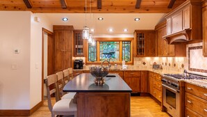 Une cuisine avec des meubles en bois, un îlot central doté d’un évier et une cuisinière.