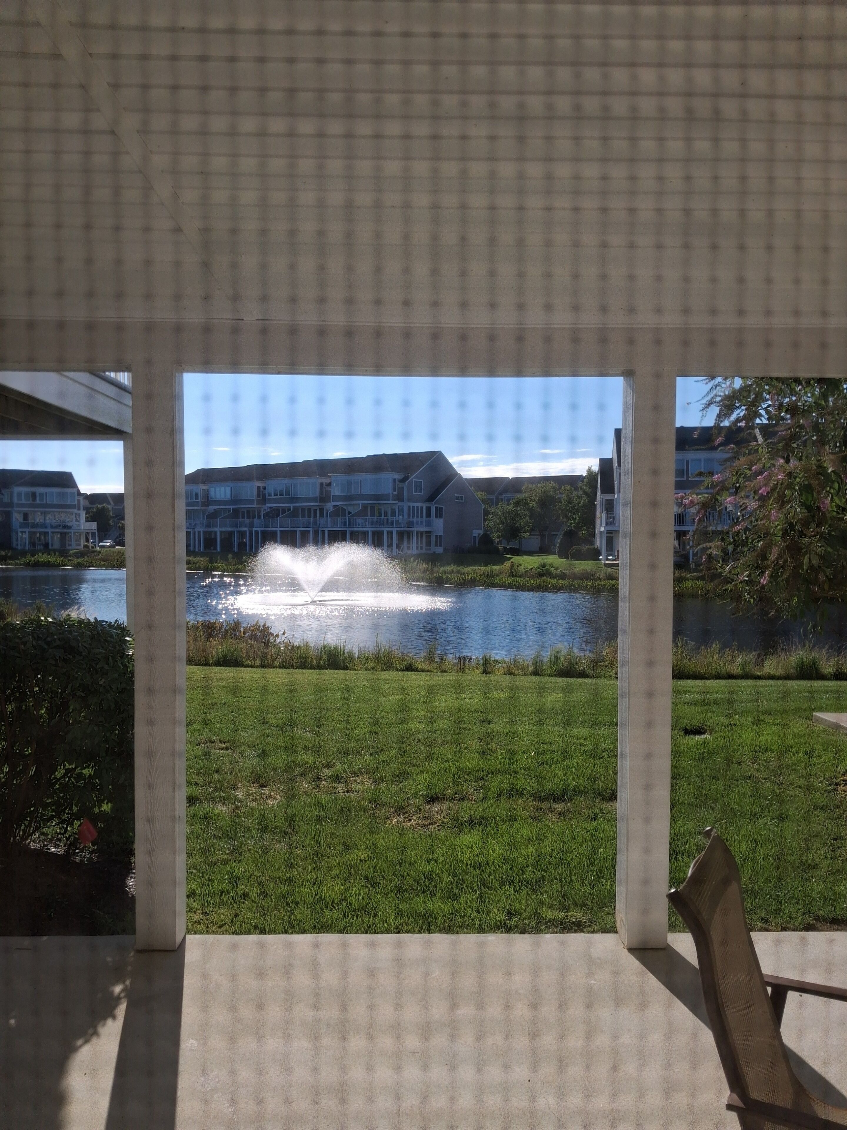 A covered outdoor area with a view of a lake and buildings in the background.