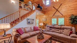Un salon spacieux avec un escalier en bois, des canapés en cuir et une décoration rustique.
