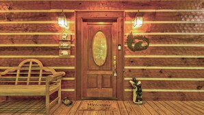 L’entrée d’un chalet en bois, avec un banc, un paillasson et une statue d’ours.