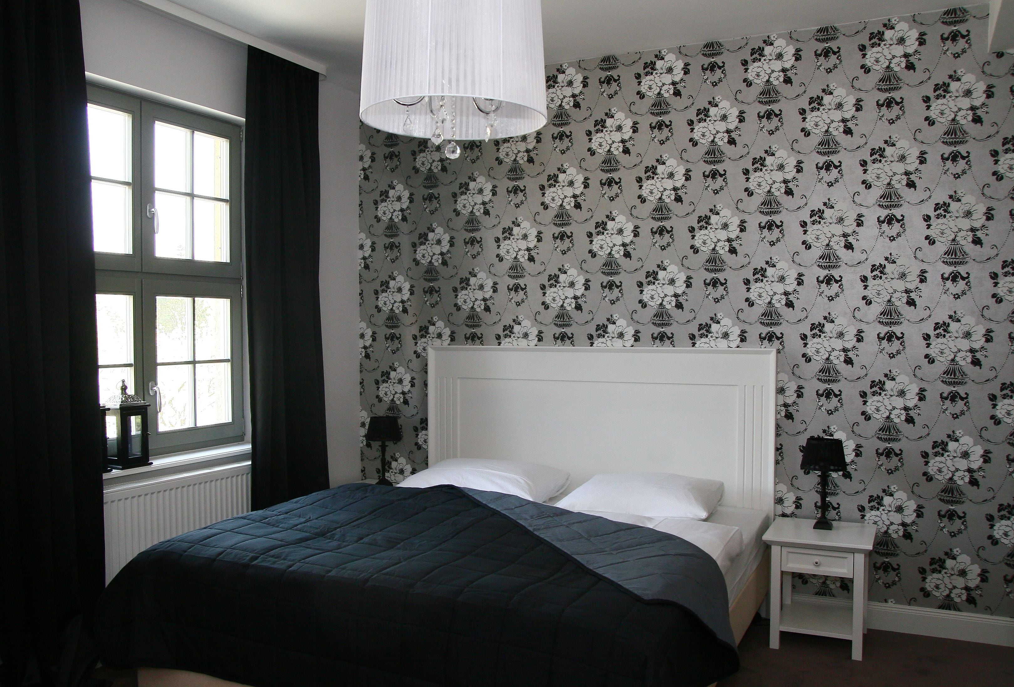 A bedroom with a bed, a nightstand, a lamp, and a window with curtains.