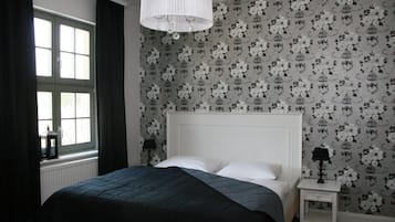 A bedroom with a bed, a nightstand, a lamp, and a window with curtains.