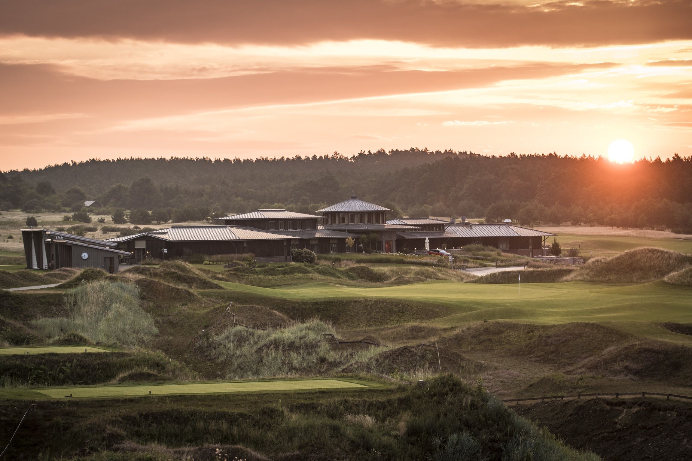 Un parcours de golf doté d’un club-house et d’un grand bâtiment surmonté d’un dôme.