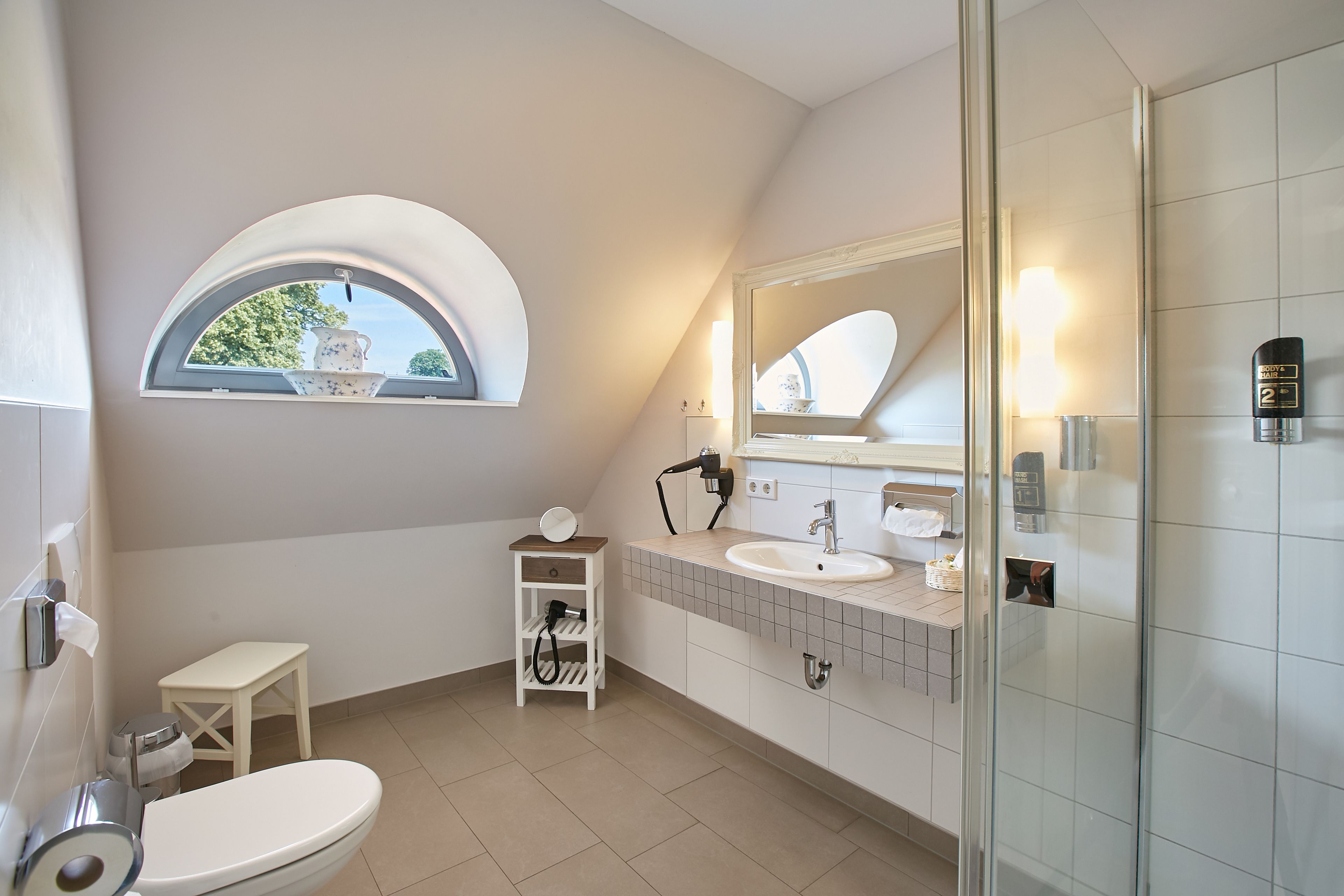 A modern bathroom with a skylight, a toilet, a sink, and a shower.