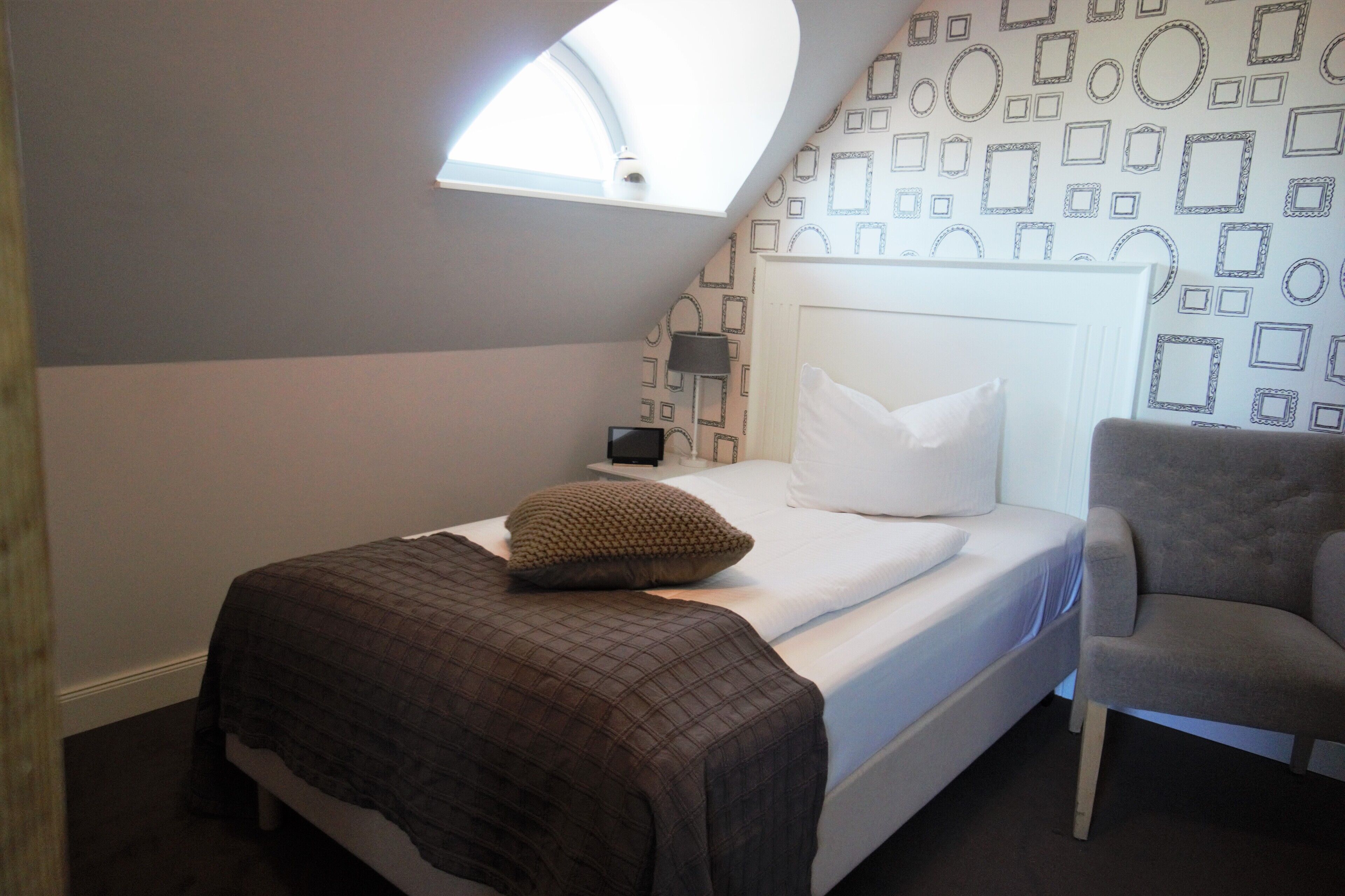 Ein Schlafzimmer mit Bett, Stuhl, Nachttisch und Dachfenster.