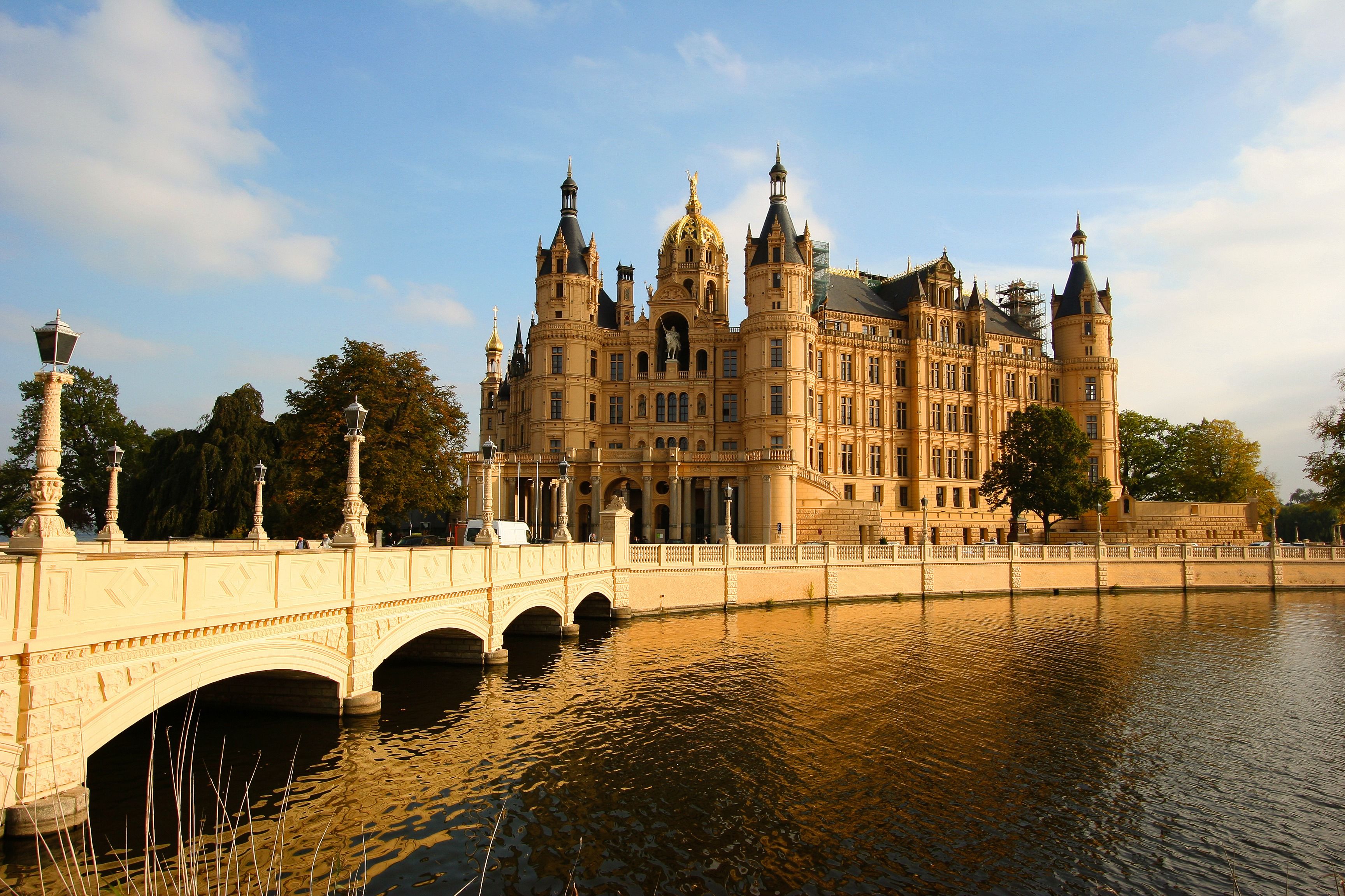 A historic building with a large central dome, multiple towers, and a bridge over a body of water.