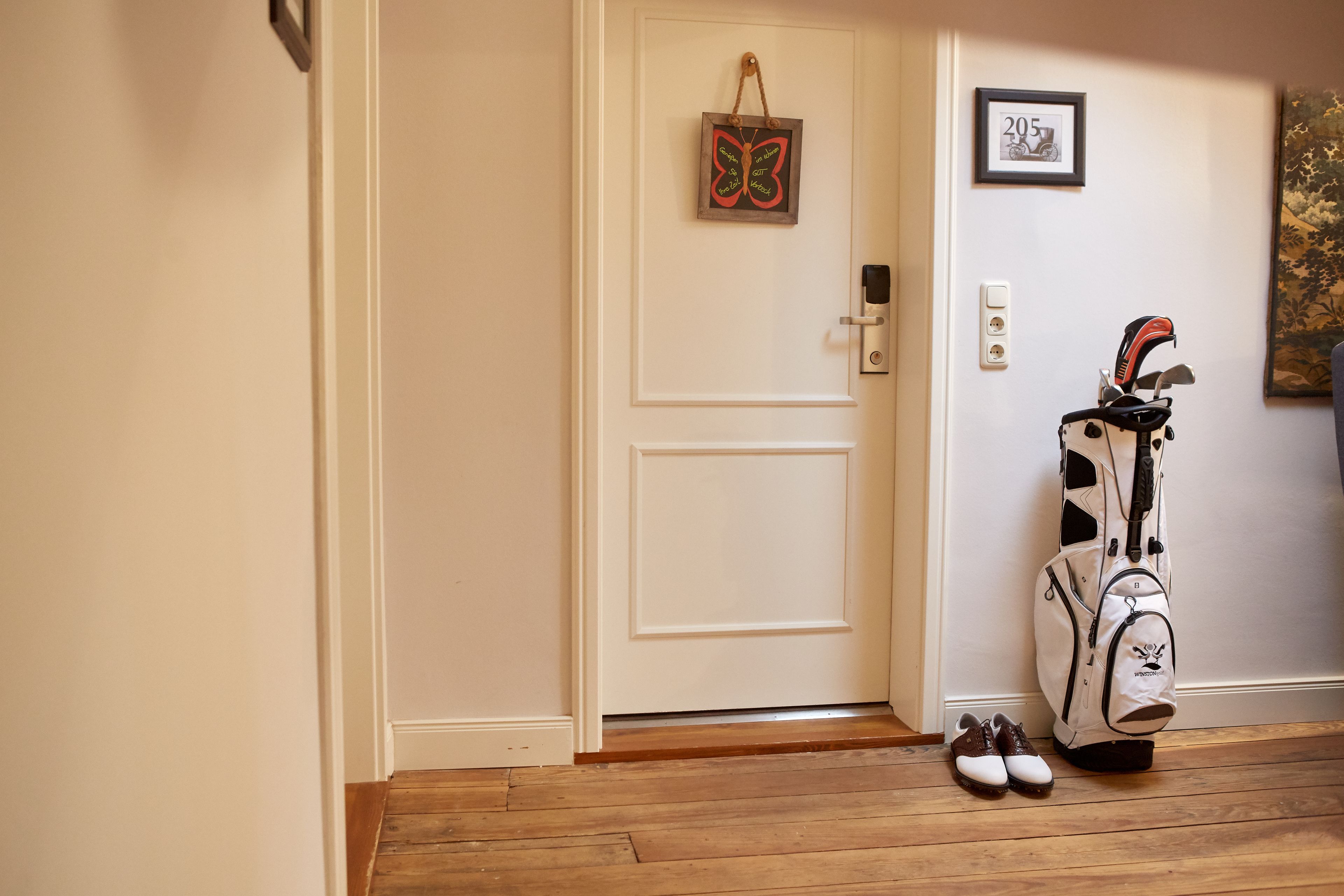 A door with a butterfly decoration, a golf bag, and a pair of shoes on the floor.