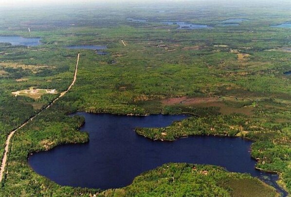 Une vue aérienne d’une vaste étendue d’eau, entourée d’une végétation luxuriante et traversée par une route sinueuse.