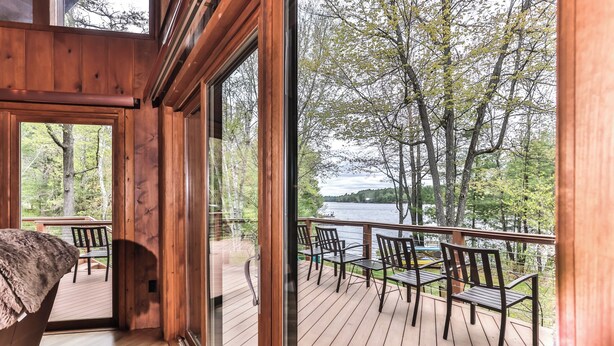 A wooden deck with outdoor seating overlooking a lake. - Gorgeous large lakefront home with firepit and a private dock! (ST GERMAIN)