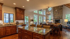 A spacious kitchen with wooden cabinets, a granite island, and large windows offering views of the outdoors.