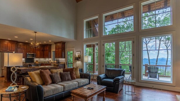 A spacious living area with a large sofa, a coffee table, and a dining area with a kitchen in the background.