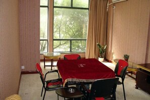 A dining area with a table covered by a red tablecloth, surrounded by chairs, and a window with curtains. - Shanghai Xinjiangnan Hotel (Shanghai)