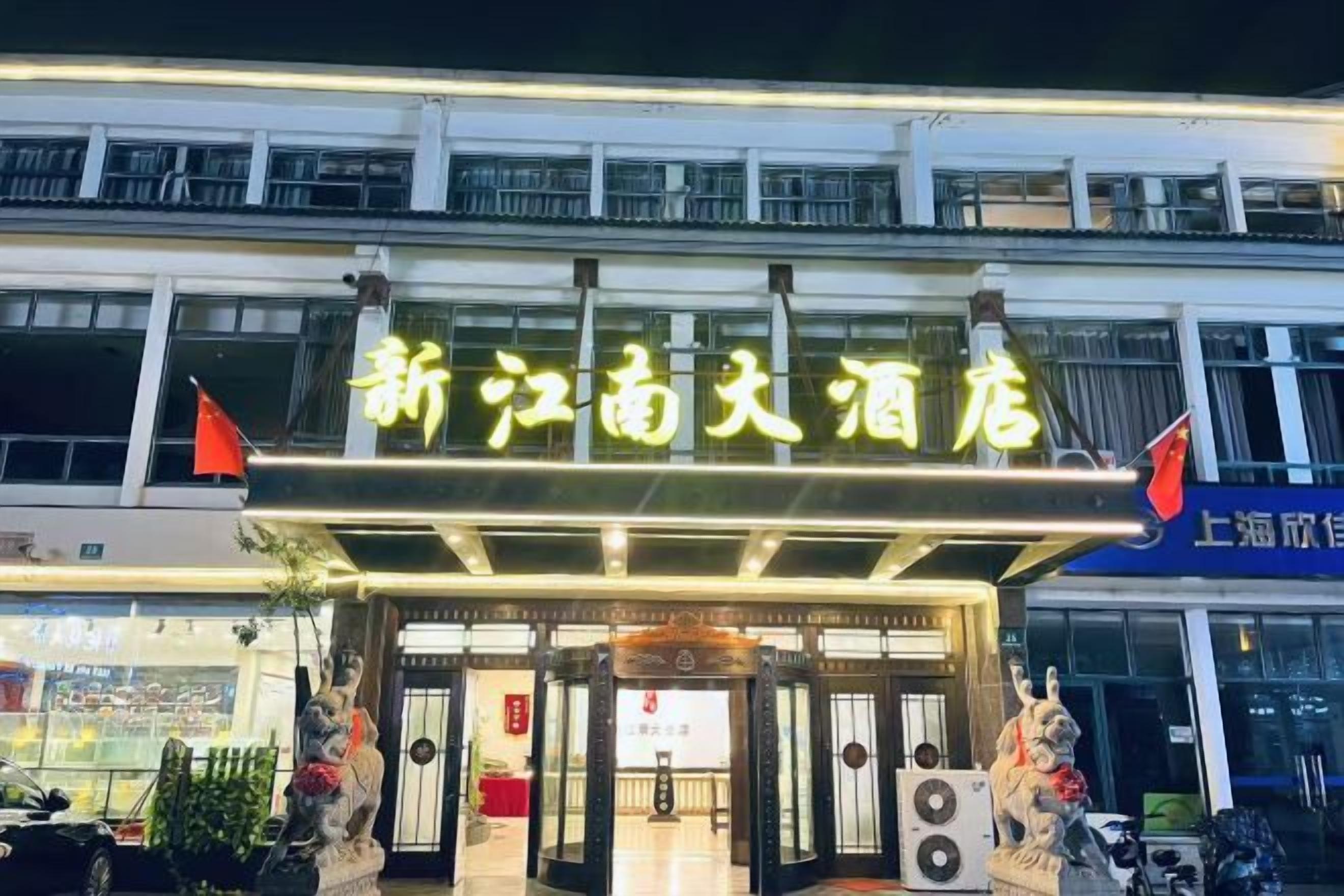 A hotel entrance with a sign, a statue, and a flag.