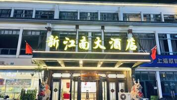 A hotel entrance with a sign, a statue, and a flag.