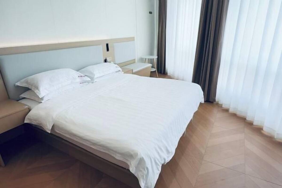Una habitación de hotel con una cama, una mesita de noche, una pequeña mesa y una ventana con cortinas.