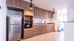 Una cocina moderna con armarios de madera, un refrigerador de acero inoxidable e iluminación colgante.