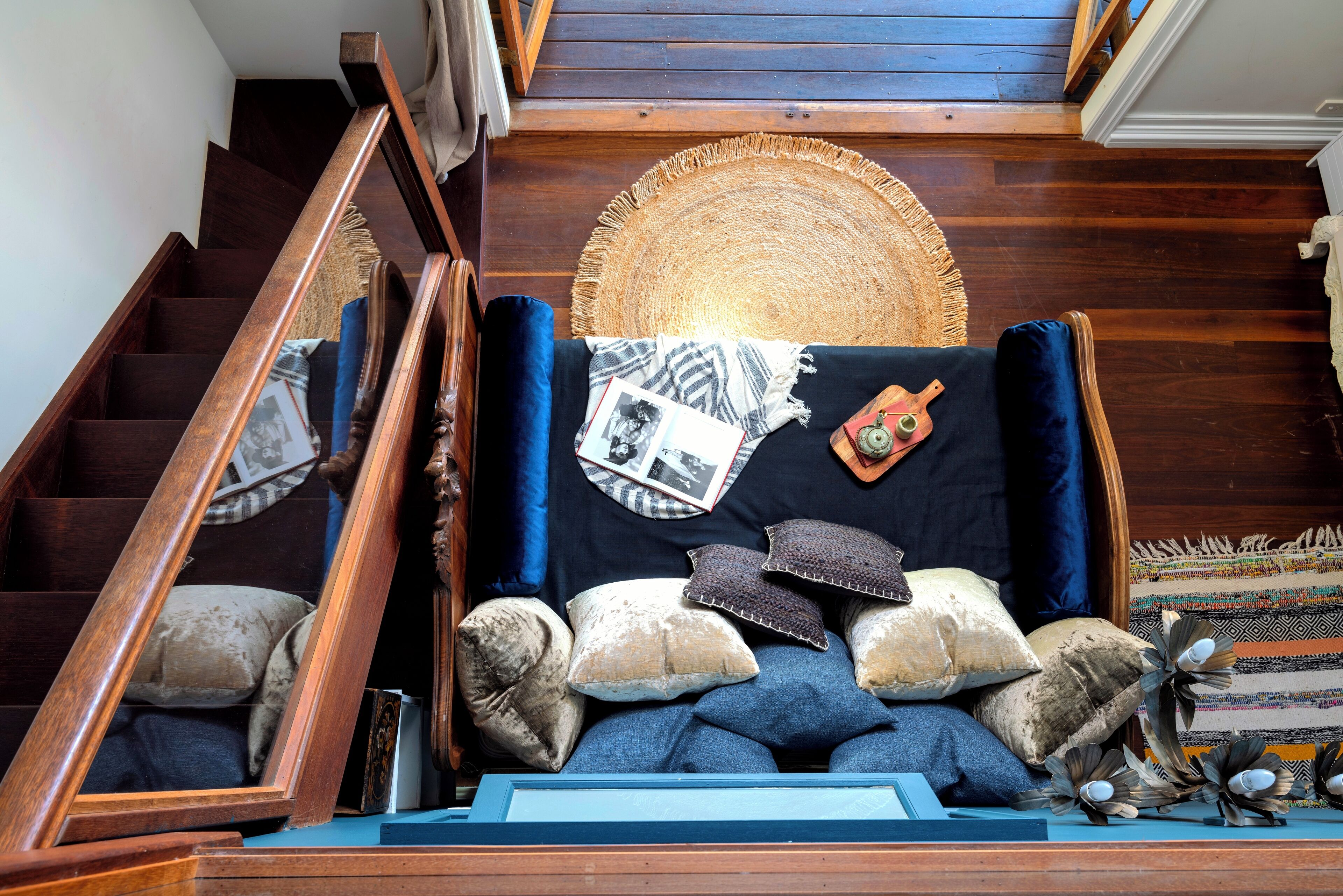 A staircase with a wooden railing and a woven rug at the top.