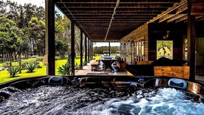 A hot tub area with a view of a garden and a building in the background. - Tranquilo Beach House (Woolgoolga)