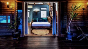 L’intérieur d’une cabane en bois, avec un lit, un escalier et un téléviseur dans un coin.
