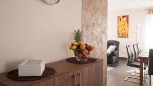 Un salon moderne avec un meuble en bois, un panier de fruits, une horloge et un tableau accroché au mur.