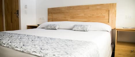 A bed with a wooden headboard, two pillows, a bedside table, and a nightstand.
