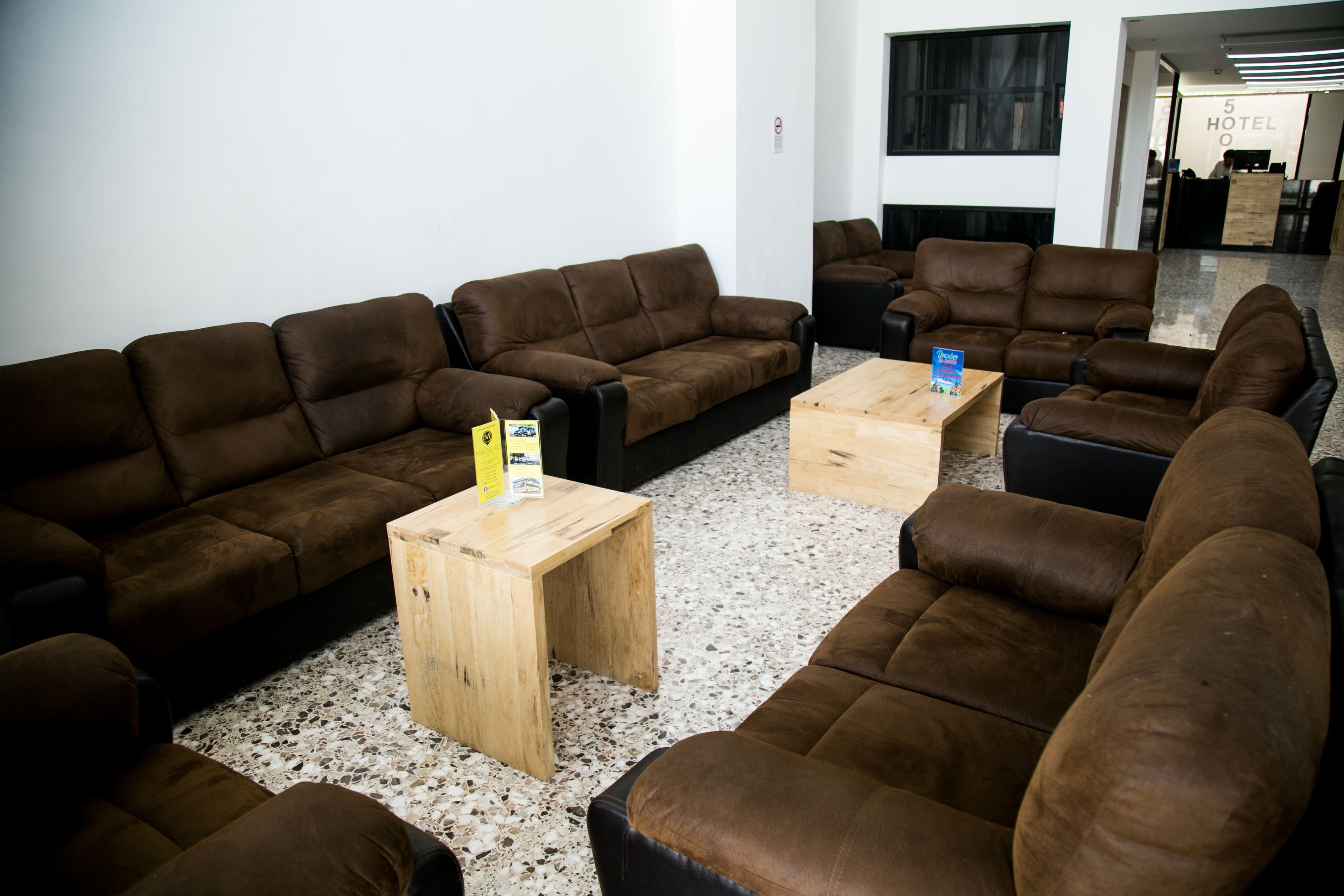 Een moderne lobby met bruine leren banken en houten salontafels.
