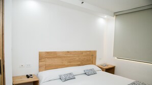 A hotel room with a wooden headboard, a white bed, two bedside tables, and a wall-mounted TV. - Hotel 500 (Monterrey)
