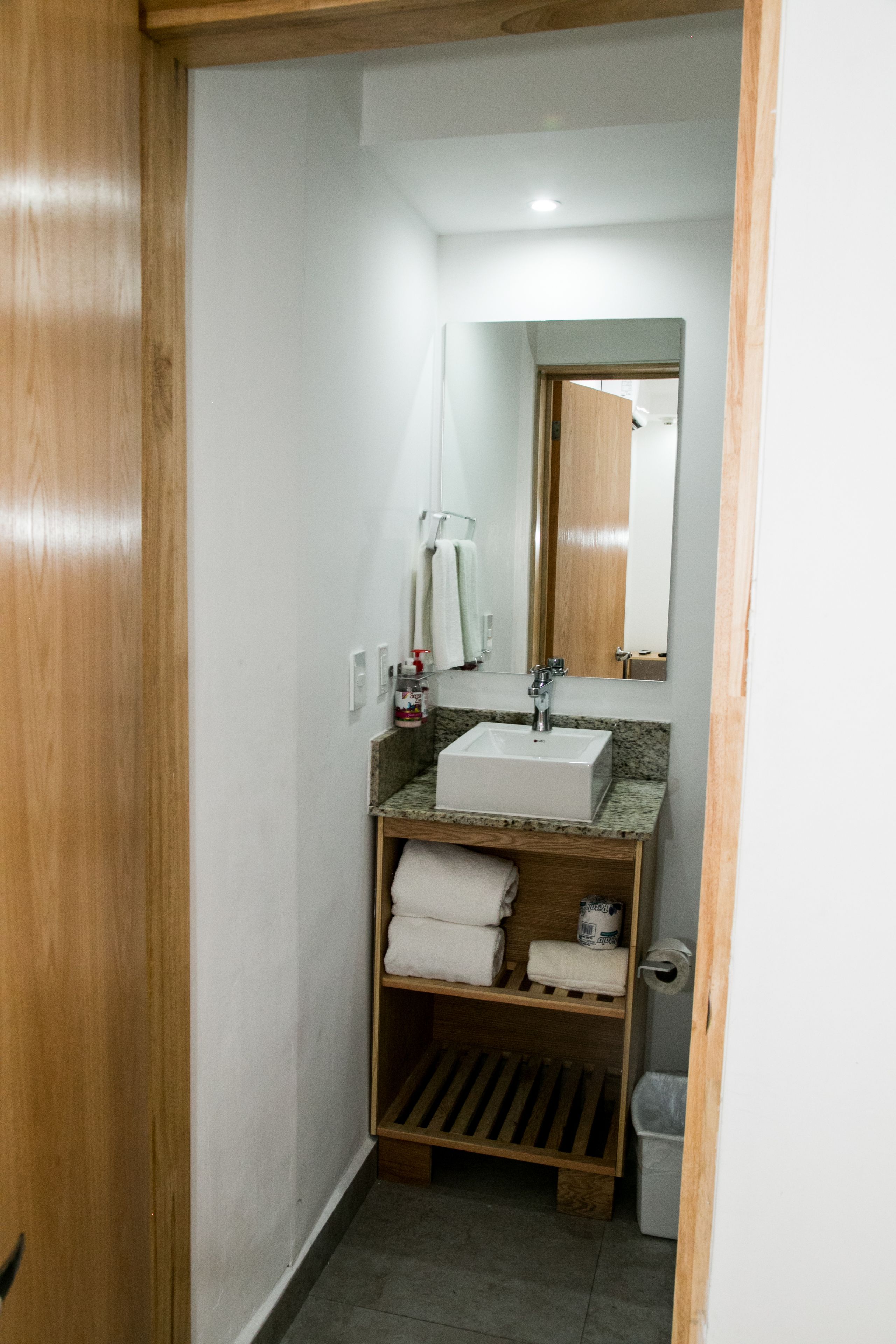 A compact bathroom with a wooden vanity, a sink, and a mirror.