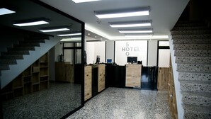 A hotel reception area with a modern design, featuring a reception desk, a staircase, and a sign indicating it is a 5-star hotel. - Hotel 500 (Monterrey)