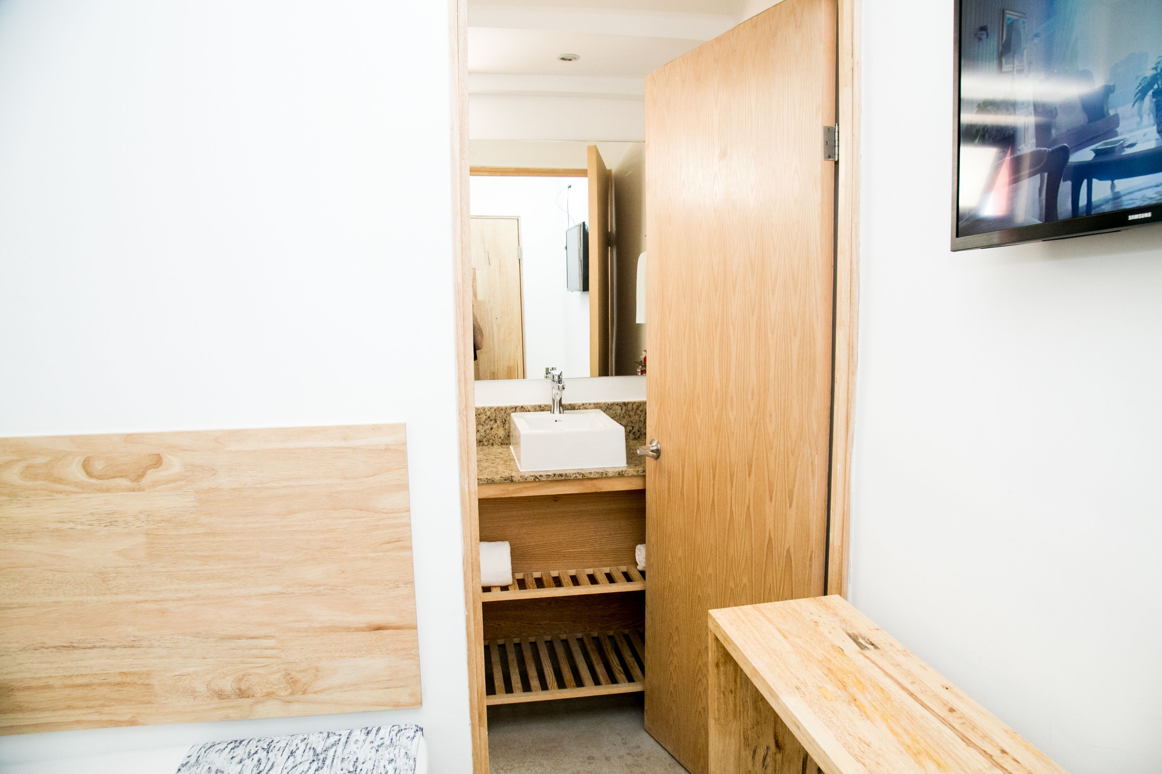 A bathroom with a wooden vanity, a sink, and a shower area.