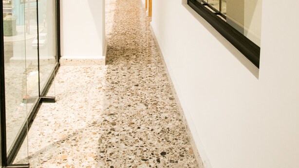 A corridor with glass walls, a terrazzo floor, and a wooden door at the end. - Hotel 500 (Monterrey)
