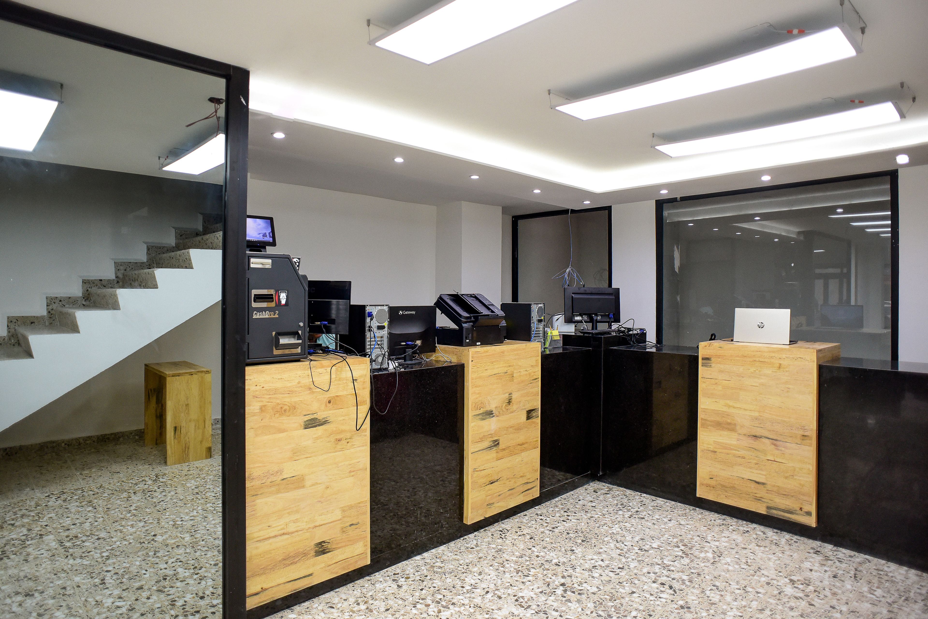 Una zona de recepción con un escritorio de madera, una computadora y un taburete pequeño.