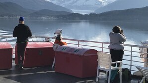 A boat with passengers overlooking a calm lake and snow-capped mountains. - At the White House (Skagway)