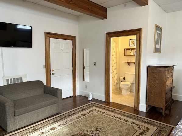 A living room with a sofa, a wooden cabinet, and a television on the wall.