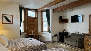 A hotel room with two beds, a TV, a desk, and a chair. - At the White House (Skagway)
