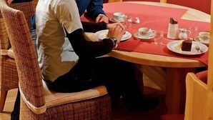 A wooden interior with a round table set for two, surrounded by red upholstered chairs. - Hotel Wieser (Mittersill)